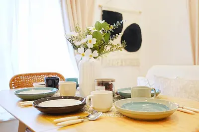 a table with plates and a vase with flowers on it at Tomo House Otsuka - from 6 minutes station \u5927\u585a \u99c5\u304b\u3089\u5f92\u6b696\u5206 in Tokyo
