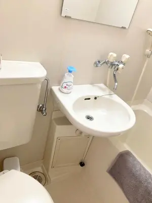 a bathroom with a white sink and a toilet at Tomo House \u897f\u65b0\u5bbf\u4e94\u4e01\u76ee\u30a2\u30d1\u30fc\u30c8 301 in Tokyo