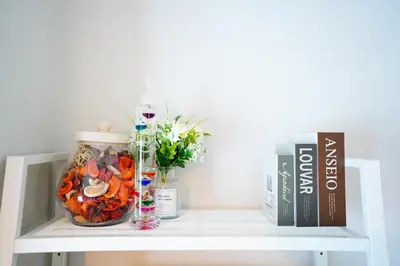 a shelf with a vase of flowers and a book at Tomo House \u897f\u65b0\u5bbf\u4e94\u4e01\u76ee\u30a2\u30d1\u30fc\u30c8 301 in Tokyo