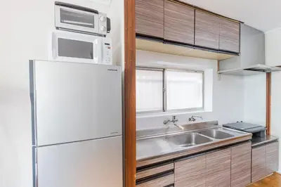 a kitchen with a white refrigerator and a sink at Hanna Inn Zoshigaya in Tokyo
