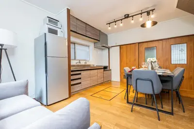 a kitchen and dining room with a table and a refrigerator at Hanna Inn Zoshigaya in Tokyo