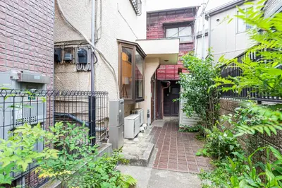 an alleyway between two buildings with plants at Hanna Inn Zoshigaya in Tokyo