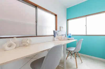 a desk and two chairs in a room with windows at Hanna Inn Zoshigaya in Tokyo