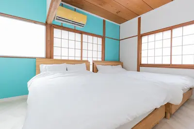 two beds in a room with two windows at Hanna Inn Zoshigaya in Tokyo
