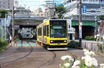 a yellow train on tracks in a city at Jr\u5c71\u624b\u7ebf\u5927\u585a\u7ad9\u6b65\u884c2\u5206\u949f \u6771\u5357\u793e3\u53f7 in Tokyo