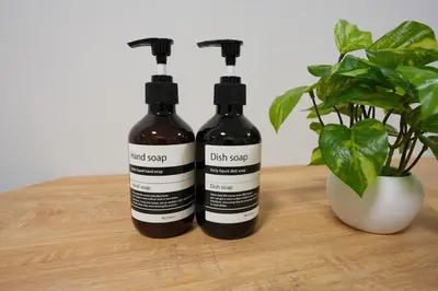 two bottles of dark soap sitting next to a plant at Aki Hiroo Stay 101 in Tokyo