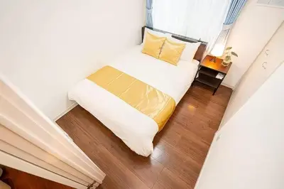 a small bedroom with a bed with white sheets and yellow pillows at lkebukuro-Five palace in Tokyo