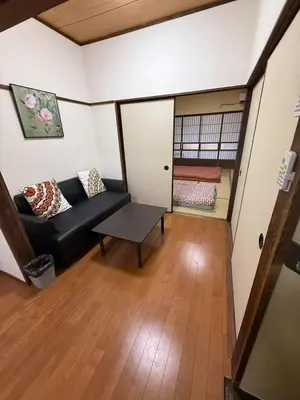 a living room with a black couch and a table at \u79cb\u53f6\u539f\u6c11\u5bbf\u6210\u7530\u7fbd\u7530\u673a\u573a\u53ef\u4ee5\u76f4\u8fbe\u6b65\u884c10\u5206\u949f\u62b5\u8fbe\u8f66\u7ad9\u4ea4\u901a\u4fbf\u5229\u5b89\u9759\u53ef\u5165\u4f4f10\u4eba in Tokyo