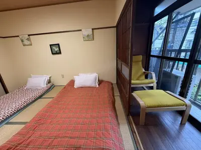 a room with two beds and a chair and a window at \u79cb\u53f6\u539f\u6c11\u5bbf\u6210\u7530\u7fbd\u7530\u673a\u573a\u53ef\u4ee5\u76f4\u8fbe\u6b65\u884c10\u5206\u949f\u62b5\u8fbe\u8f66\u7ad9\u4ea4\u901a\u4fbf\u5229\u5b89\u9759\u53ef\u5165\u4f4f10\u4eba in Tokyo
