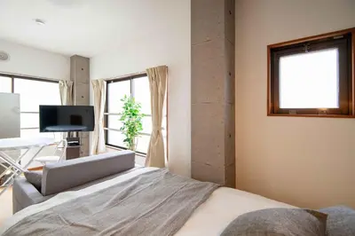 a bedroom with a bed and a tv and windows at \u5927\u6cb3\u5185\u30b3\u30fc\u30dd301 \u6700\u59273\u540d \u8cb8\u5207 \u672c\u6240\u543e\u59bb\u6a4b\u99c5\u5f92\u6b6910\u5206 20\u5e73\u7c73 in Tokyo
