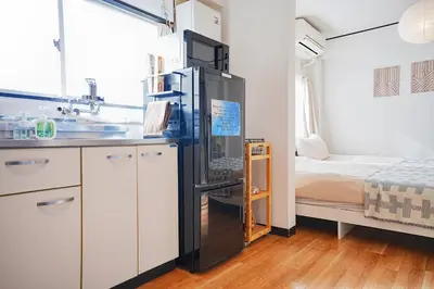 a kitchen with a refrigerator in a room with a bed at Tomo House Yoyogi 302 - from 4 minutes station \u4ee3\u3005\u6728 302 \u99c5\u304b\u3089\u5f92\u6b694\u5206 in Tokyo