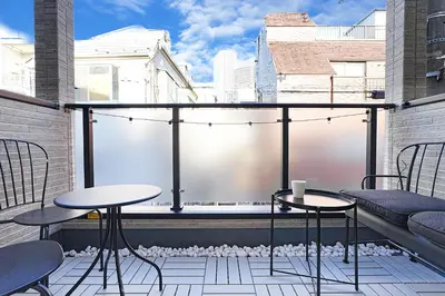 a balcony with two tables and chairs on a roof at Tomo House Nishi-Shinjuku-Gochome - from 3 minutes station \u897f\u65b0\u5bbf\u6238\u5efa\u3066 \u99c5\u304b\u3089\u5f92\u6b693\u5206 in Tokyo