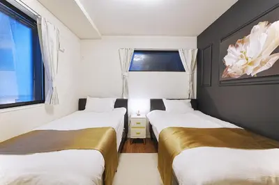 two beds in a room with two windows at Tomo House Nishi-Shinjuku-Gochome - from 3 minutes station \u897f\u65b0\u5bbf\u6238\u5efa\u3066 \u99c5\u304b\u3089\u5f92\u6b693\u5206 in Tokyo