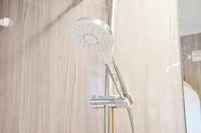 a shower head in front of a curtain at Tomo House Nishi-Shinjuku-Gochome - from 3 minutes station \u897f\u65b0\u5bbf\u6238\u5efa\u3066 \u99c5\u304b\u3089\u5f92\u6b693\u5206 in Tokyo