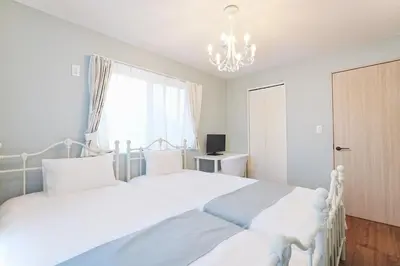 a white bedroom with two beds and a chandelier at Tomo House Nishi-Shinjuku-Gochome - from 3 minutes station \u897f\u65b0\u5bbf\u6238\u5efa\u3066 \u99c5\u304b\u3089\u5f92\u6b693\u5206 in Tokyo