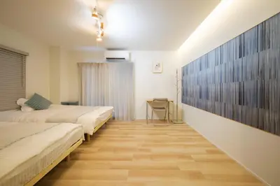 a bedroom with two beds and a wooden floor at Breeze Stay Shiohama in Tokyo