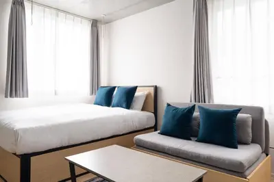 a bedroom with a bed and a couch with blue pillows at PASEO\u5e02\u8c37\u53f0\u753all in Tokyo