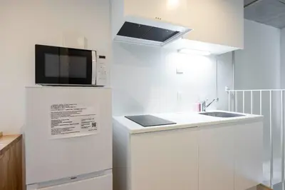 a white kitchen with a microwave and a sink at PASEO\u5e02\u8c37\u53f0\u753all in Tokyo