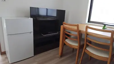 a kitchen with a table and two chairs and a refrigerator at \u5fa1\u5bbf\u7dba\u7f85\u91cc1 in Tokyo