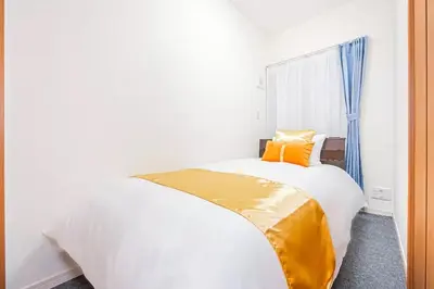 a bedroom with a large white bed with orange pillows at Akihabara Skytree Premium Apartment 302 in Tokyo