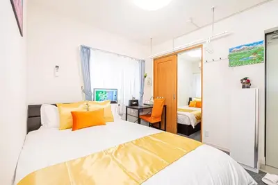 a bedroom with a bed with orange pillows and a desk at Akihabara Skytree Premium Apartment 302 in Tokyo