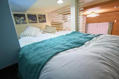a large white bed with a blue blanket on it at Hotel Little Stay Tateishi 1F in Tokyo