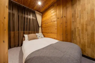 a bedroom with a bed and a wooden wall at Shinjuku Homely Stay in Tokyo