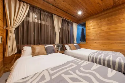 two beds in a room with wooden walls at Shinjuku Homely Stay in Tokyo