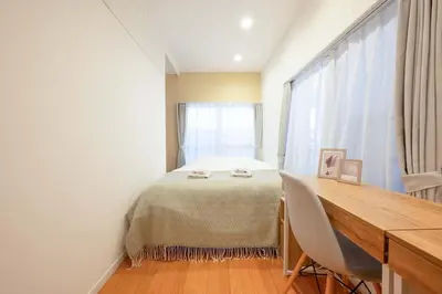 a bedroom with a bed and a desk and a window at Guest Residence Kanamecho in Tokyo