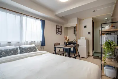 a bedroom with a bed and a table and a kitchen at CraftFlat Numabukuro 305, uphill residence monthly stay in Tokyo