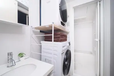 a white bathroom with a washing machine and a sink at Monzen-nakacho 1LDK with projector, 2 double beds,301 in Tokyo