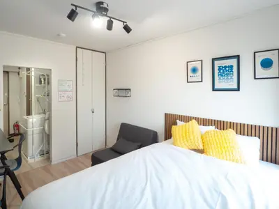 a bedroom with a large bed and a chair at UPHouse 2C Gotokuji in Tokyo