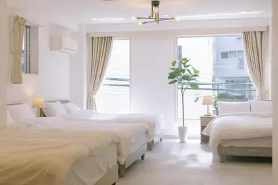 a white bedroom with two beds and a window at 8min walk from Shibuya Sta in Tokyo