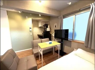 a room with a bed and a table and a couch at \u4e95\u4e0a\u9054\u4e5f\u8a2d\u8a08\u73fe\u4ee3\u98a8\u65c5\u9928 \u4eac\u6210\u7dda\u99c51\u5206 \u90fd\u5fc3\u79fb\u52d5\u4fbf\u5229 \u8fd1\u5317\u5343\u4f4f\u4e0a\u91ce\u6d45\u8349\u9280\u5ea7\u30b9\u30ab\u30a4\u30c4\u30ea\u30fc Wifi\u9577\u671f\u53ef WAGAMAMA\u5343\u4f4fS03\u5ba4 Y01\u5ba4 Y03\u5ba4 in Tokyo