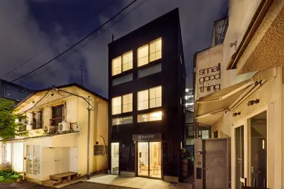 a black building with lit windows on a street at \u30de\u30a4\u30b0\u30ec petit \u6e0b\u8c37\u539f\u5bbf in Tokyo