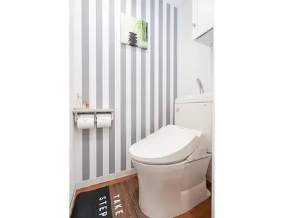 a bathroom with a white toilet and striped walls at My Sumida Home 2A in Tokyo