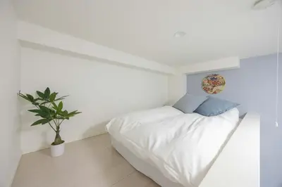 a white bedroom with a bed and a potted plant at ParkSide \u5927\u4e45\u4fdd\u99c5\u5f92\u6b6910\u5206 \u97d3\u56fd\u30b0\u30eb\u30e1\u3092\u697d\u3057\u3080 \u65b0\u5bbf \u6e0b\u8c37 \u539f\u5bbf\u3078\u597d\u30a2\u30af\u30bb\u30b9 \u6700\u59272\u540d in Tokyo