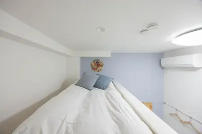 a bedroom with a bed with two blue pillows on it at ParkSide \u5927\u4e45\u4fdd\u99c5\u5f92\u6b6910\u5206 \u97d3\u56fd\u30b0\u30eb\u30e1\u3092\u697d\u3057\u3080 \u65b0\u5bbf \u6e0b\u8c37 \u539f\u5bbf\u3078\u597d\u30a2\u30af\u30bb\u30b9 \u6700\u59272\u540d in Tokyo