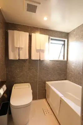 a bathroom with a white toilet and a bath tub at the Moto Hotel Ueno in Tokyo