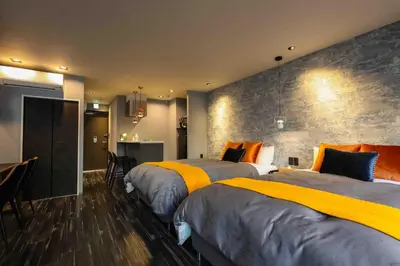 a bedroom with two beds and a kitchen with a table at the Moto Hotel Ueno in Tokyo