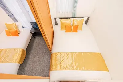 two beds in a small room with orange pillows at Akihabara Skytree Premium Apartment 401 in Tokyo
