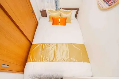 a bed in a small room with yellow and orange pillows at Akihabara Skytree Premium Apartment 501 in Tokyo