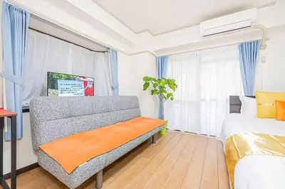 a bedroom with a couch and a bed with blue curtains at My Sumida Home 2B in Tokyo