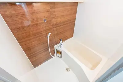 a bathroom with a white tub and a wooden wall at My Sumida Home 2B in Tokyo