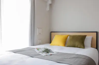 a bed with yellow pillows and a book on it at The Parkcross\u83ca\u5ddd in Tokyo