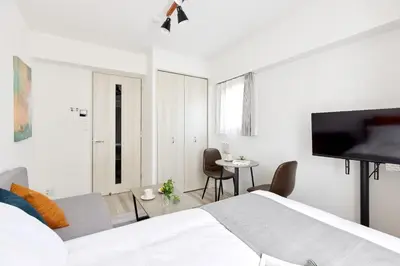 a white bedroom with a bed and a tv at The Parkcross\u83ca\u5ddd in Tokyo
