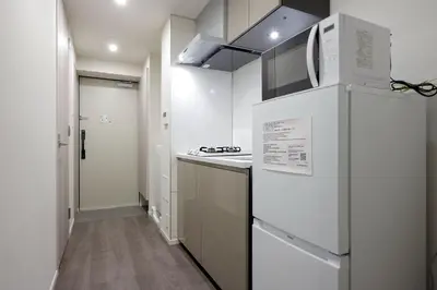 a white kitchen with a refrigerator and a stove at The Parkcross\u83ca\u5ddd in Tokyo