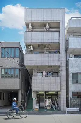 a man riding a bike in front of a building at Kinshicho First Rooftop in Tokyo