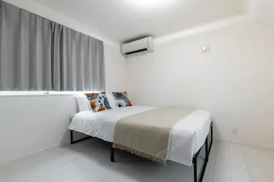 a white bedroom with a bed and a window at Conveniently located 10 min walk from Shin-Okubo Station and 7 min walk from Higashi-Shinjuku Station -Okubo hosuse- in Tokyo
