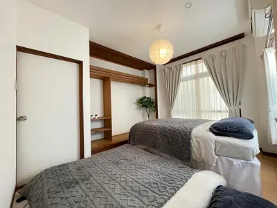 a bedroom with two beds and a window at Poco Inn in Tokyo